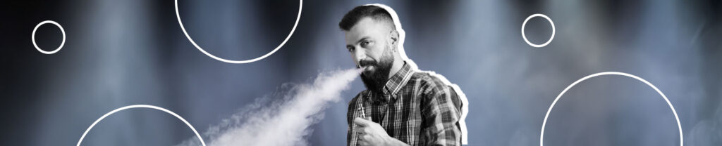 homem de barba e camisa xadrez soltando fumaça após fumar cigarro eletrônico.
